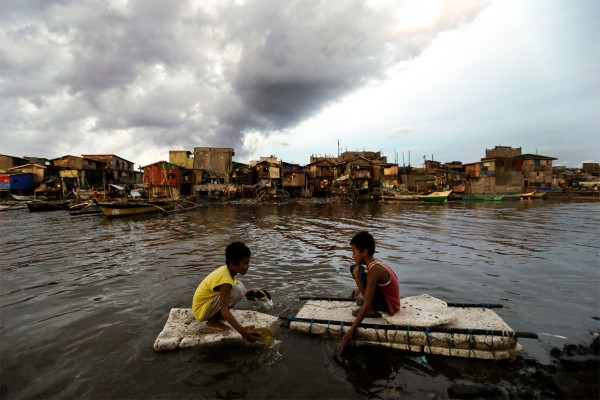 Children paddle in water in Navotas City, Philippines. (CNS photo/Ritchie B. Tongo, EPA)