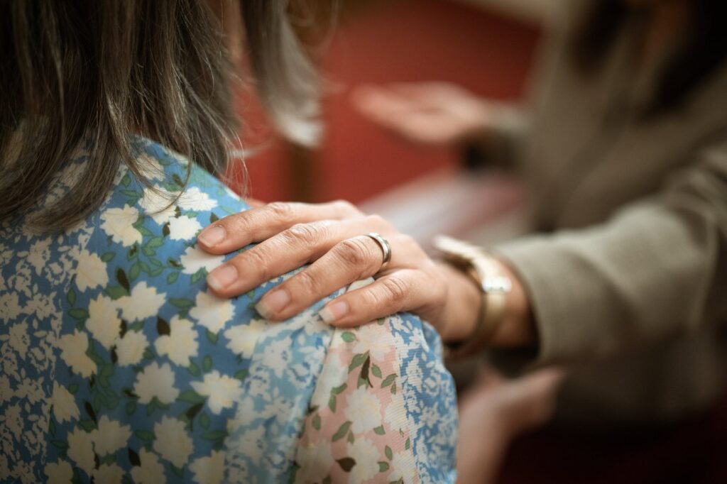 Closeup of a comforting hand on a woman's shoulder