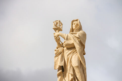 st clare statue as she is holding a lamp with a white background