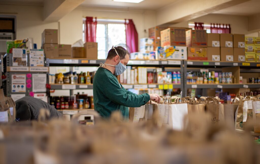 Young male volunteer packing bags of groceries in a food pantry