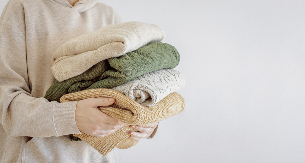Woman carrying pile of folded sweaters