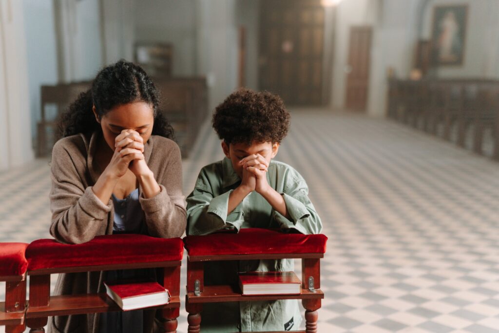 A mother and son kneeling church.