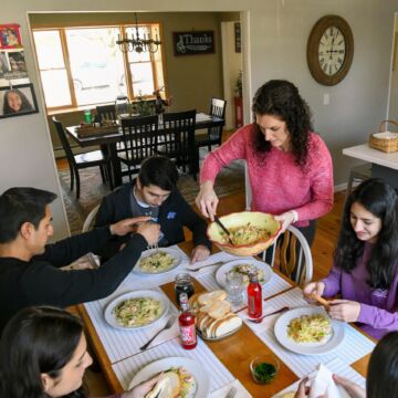 Mother serves dinner to family at table