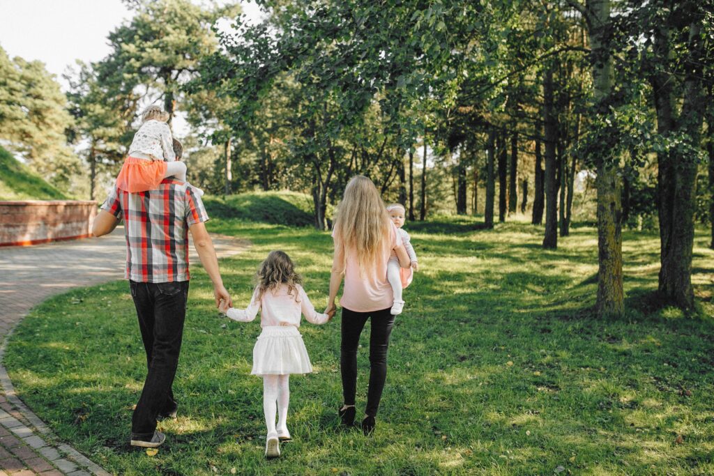 Image of young family with three children walking in a park
