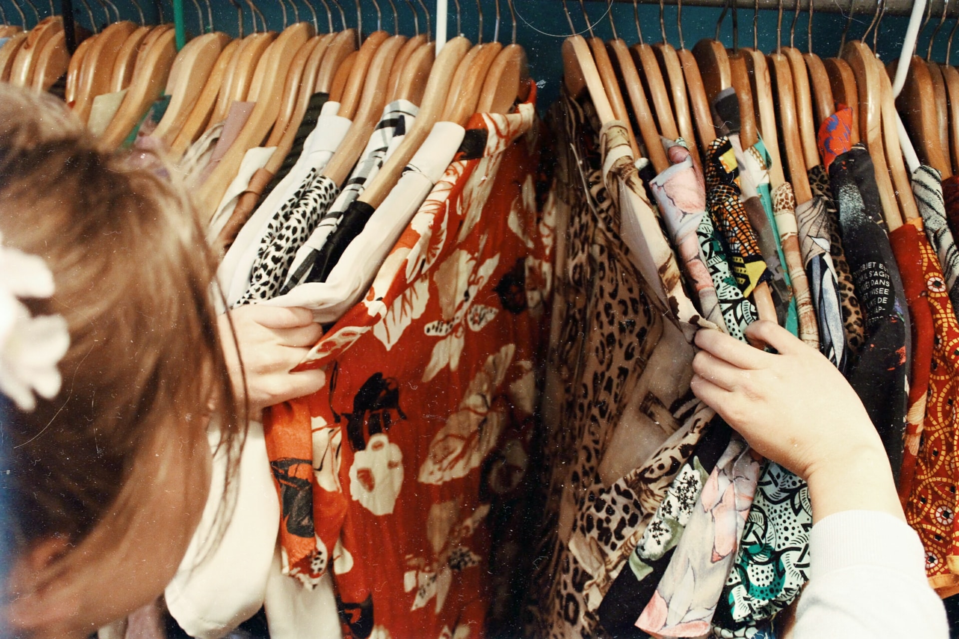 Young woman looking through patterned shirts in closet
