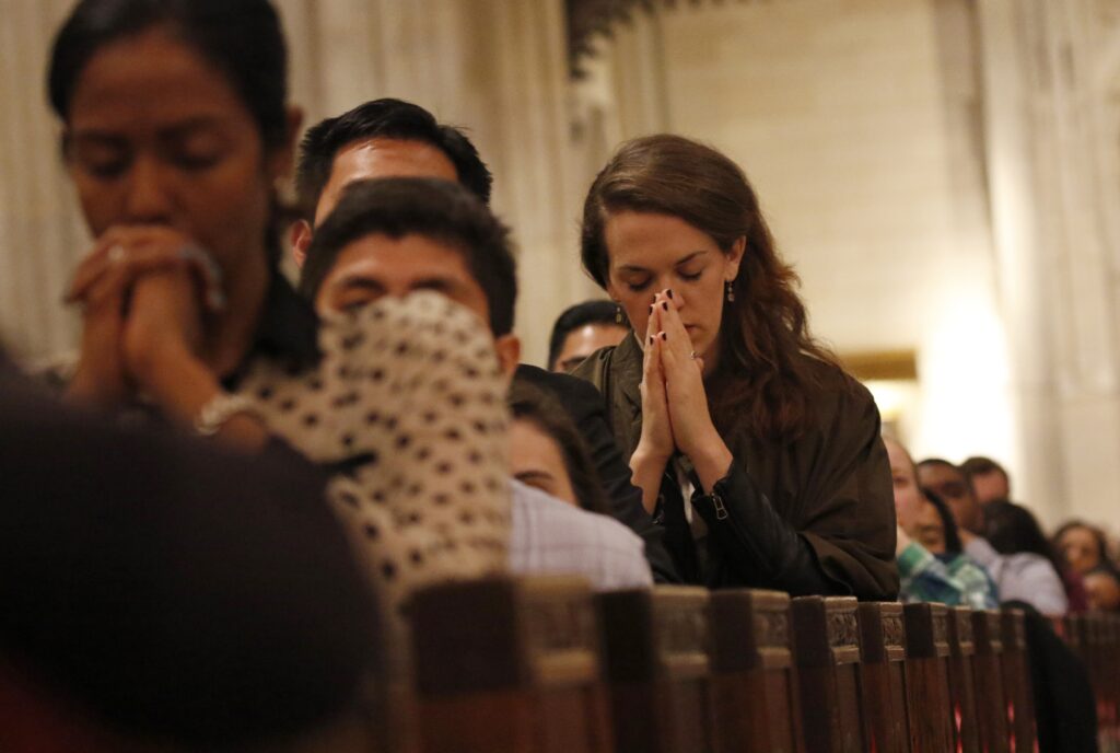 Young adults knelt in prayer during mass