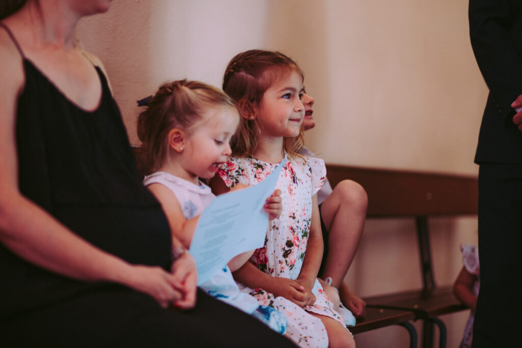 A pregnant women and two young girls sit in a pew in Church