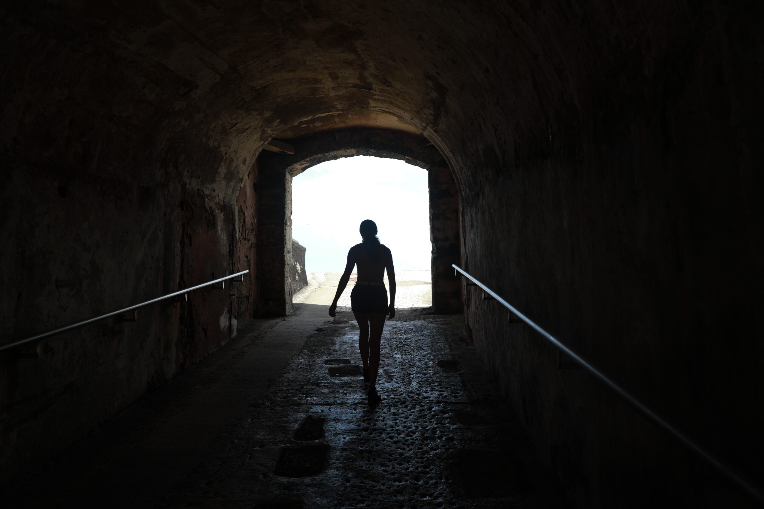 silhouette of person walking alone in a tunnel