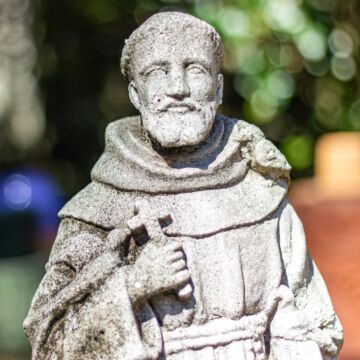 Stone Statue of Saint Francis of Assisi holding a cross.